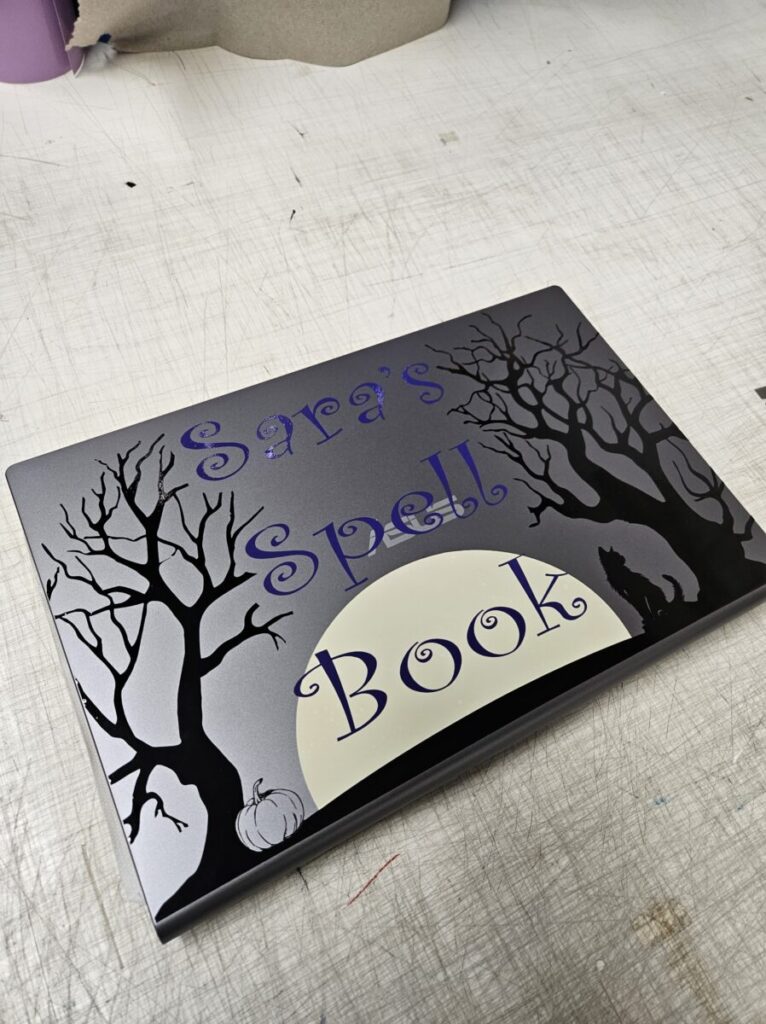 A book with a black cover depicting trees and a moon, reminiscent of the aesthetic found in vinyl signs & banners in Ann Arbor.